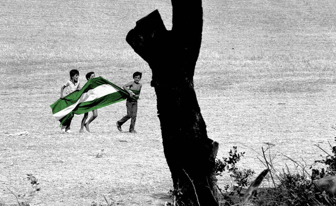 Foto de tres niños con la bandera de Andalucía en los años 70